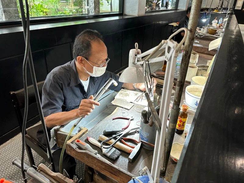 A master gemologist in a face mask examining a stone at his workbench with precision tools