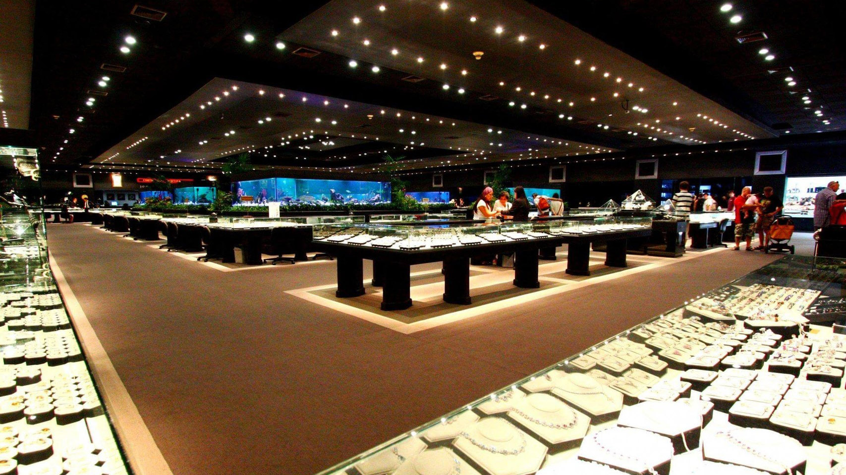 Gems Gallery showroom floor with rows of lit jewelry display counters under a dark ceiling